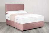 Pink bed frame with white mattress and pillows on a light wooden floor.