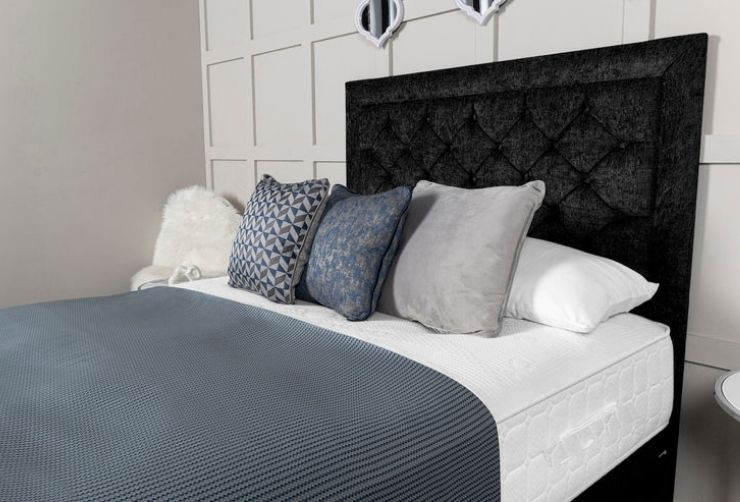 Bed with black upholstered headboard and decorative pillows in a bedroom setting.