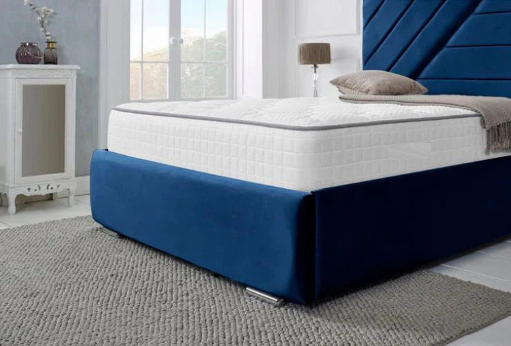 White mattress on a blue bed frame in a bedroom setting.