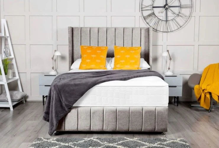 Bedroom with a gray upholstered bed, white mattress, gray blanket, and yellow pillows.