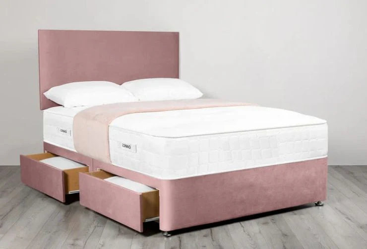 Pink bed with white mattress and pillows on a light wooden floor.