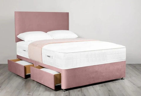 Pink bed with white mattress and pillows on a light wooden floor.
