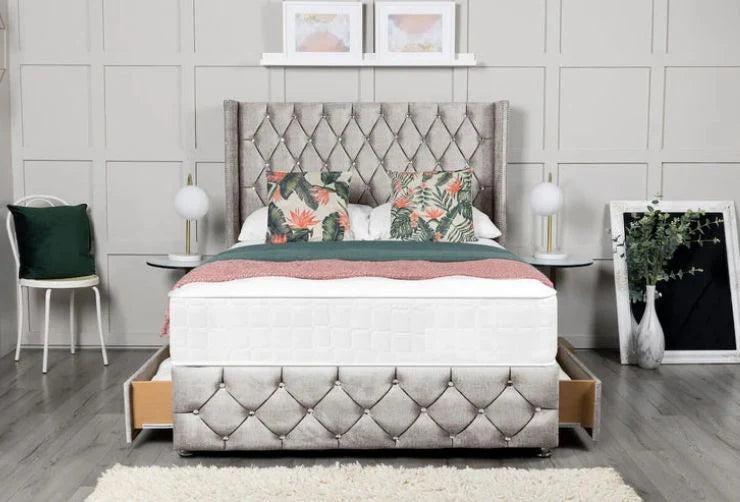 Gray upholstered bed with floral pillows in a bedroom setting.