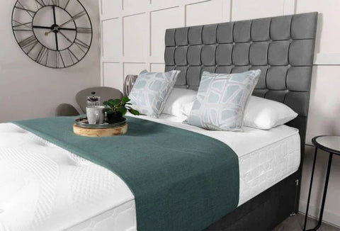 Bedroom with a gray upholstered headboard, white bedding, and decorative elements.