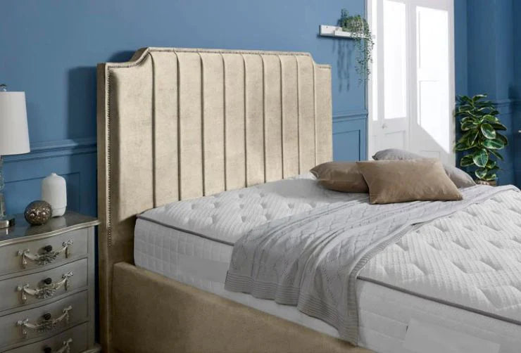 Beige upholstered bed with white bedding against a blue wall