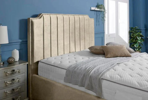 Beige upholstered bed with white bedding against a blue wall