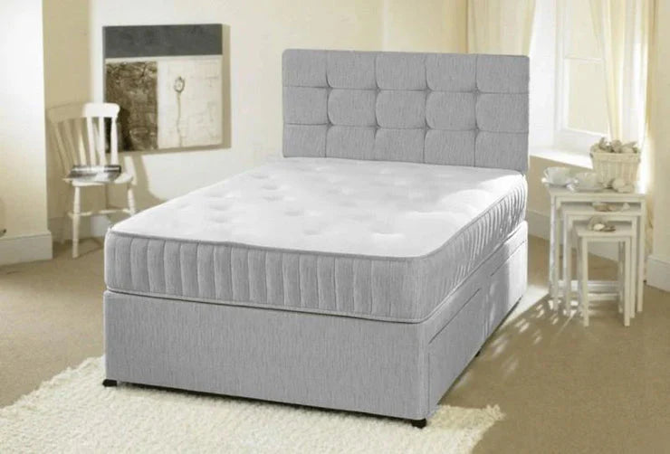 Gray upholstered bed in a bedroom setting with a mirror and small table.